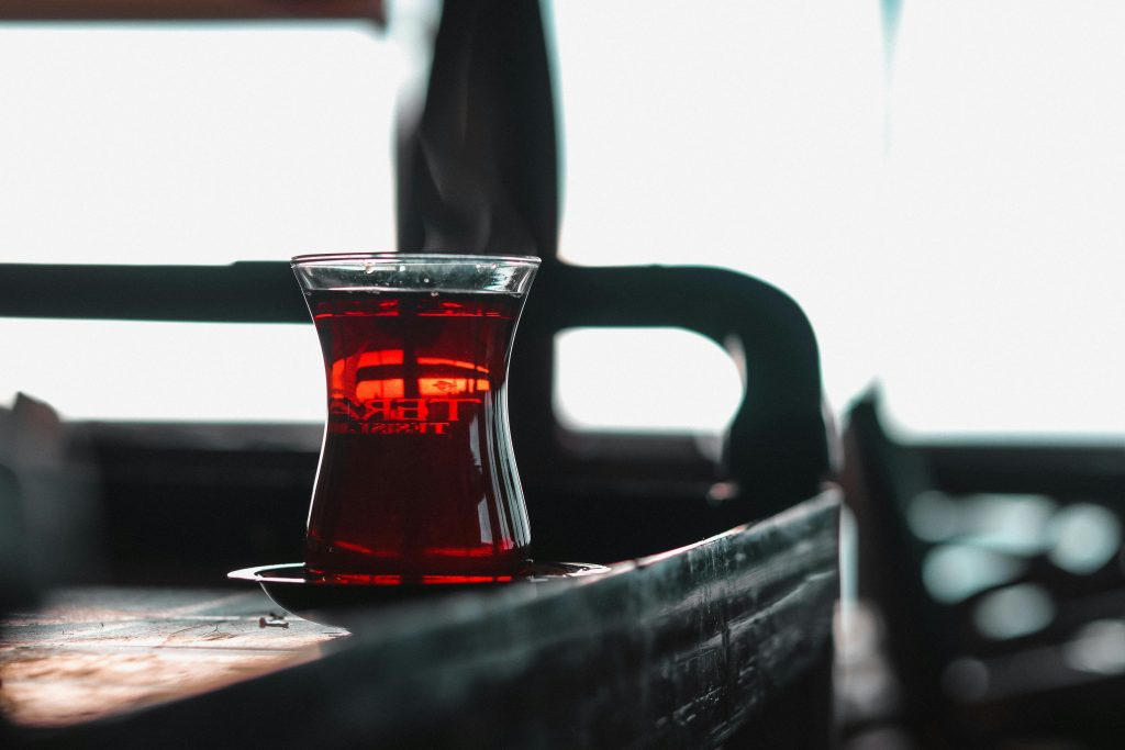 A glass of Turkish tea elegantly placed on a wooden table, captured indoors.