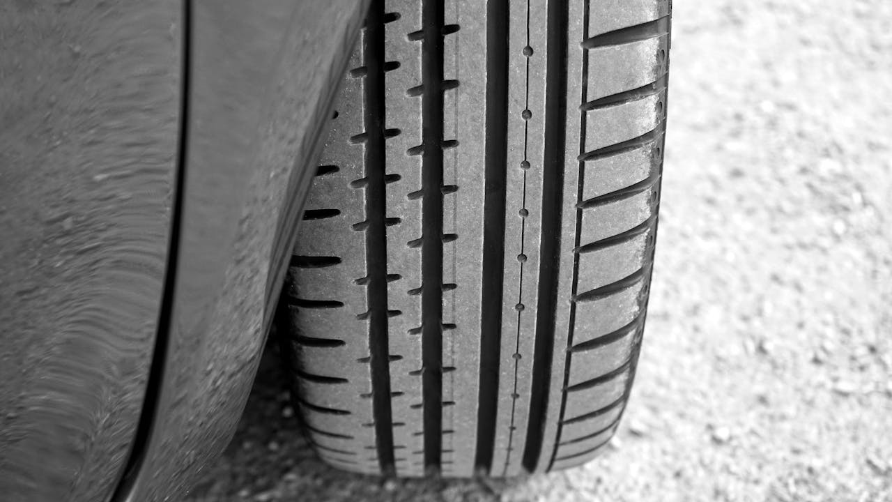 about-us Detailed view of vehicle tire on a gravel surface, showcasing tread pattern.