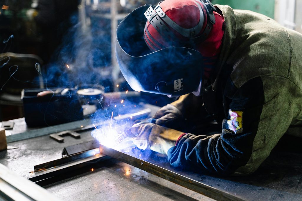 pexels photo 2381463 2381463 A welder works on metal fabrication indoors, creating bright sparks and smoke.