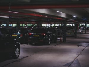 A dimly lit underground parking garage filled with parked cars and visible entrance signs.