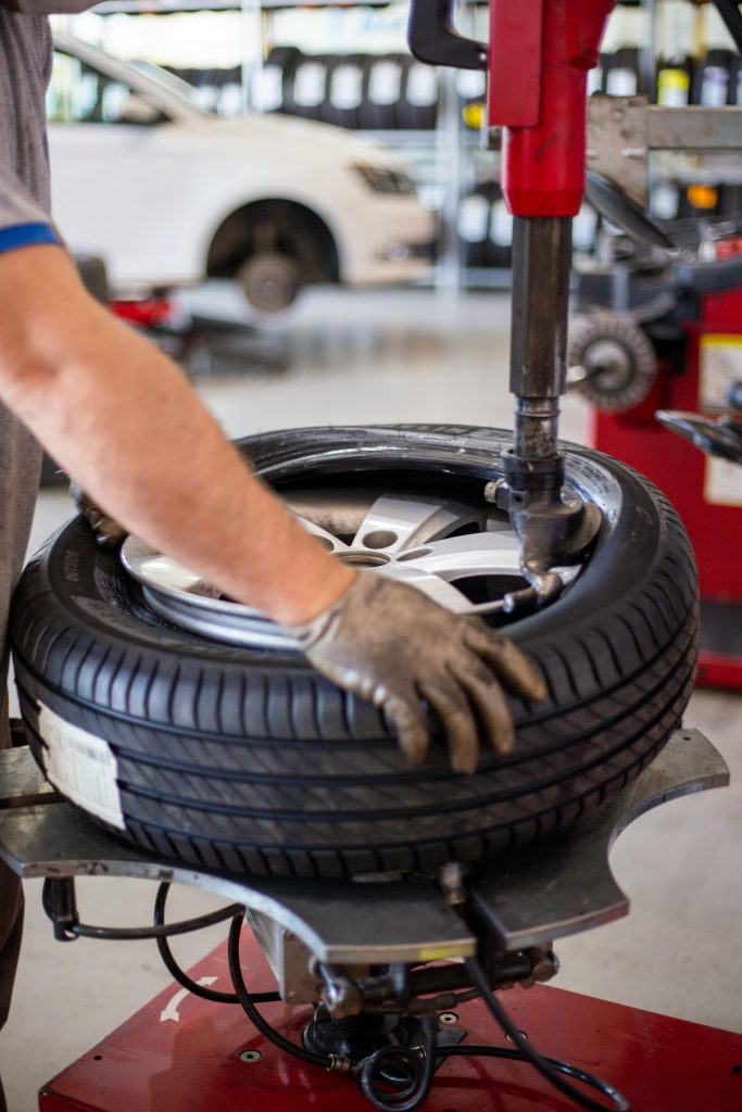 pexels photo 5260115 5260115 Close-up of an auto mechanic changing a tire with precision equipment in a professional workshop.