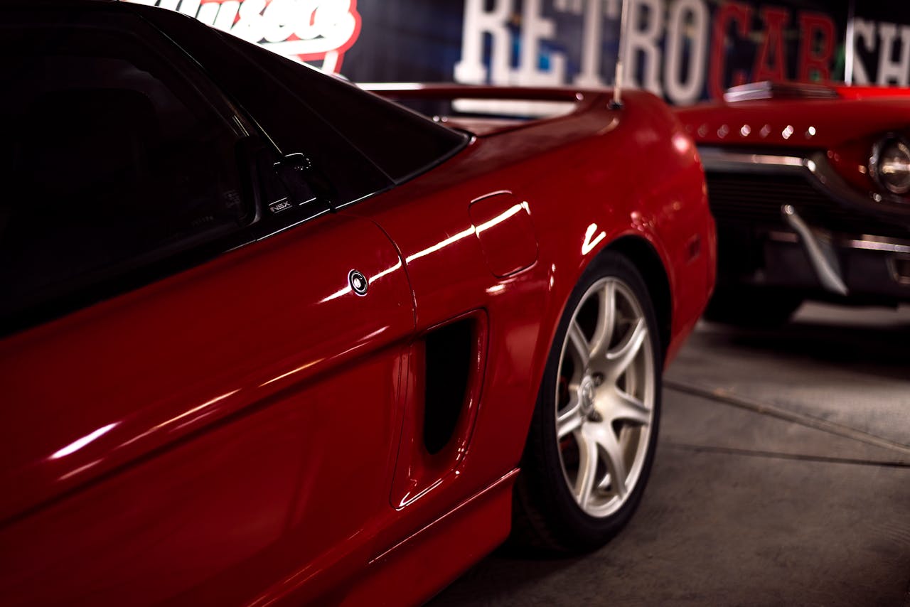 Close-up of a red vintage sports car parked in a retro-themed garage, emphasizing style and design.