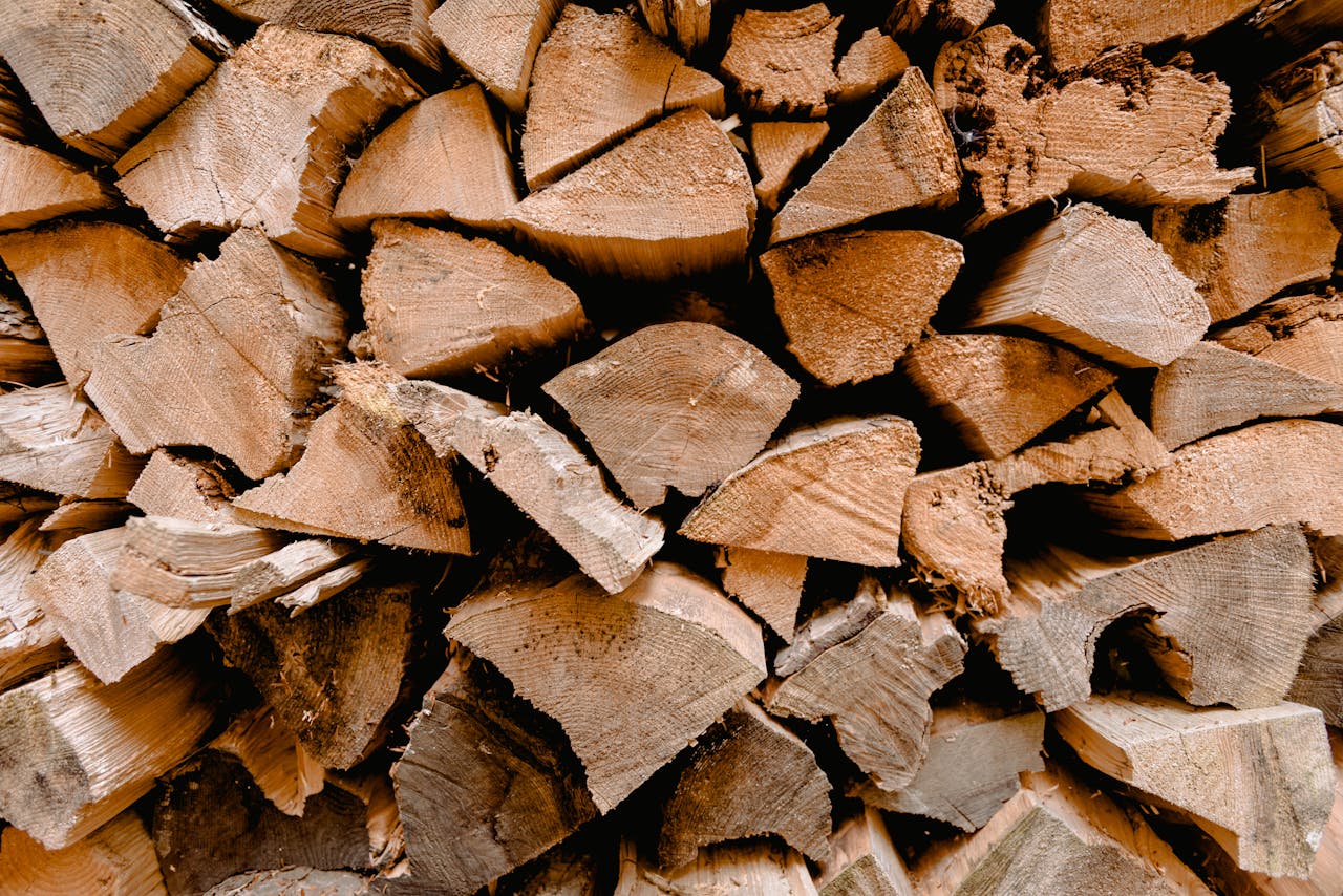 Close-up view of a neatly stacked pile of chopped firewood, displaying rough and textured surfaces.