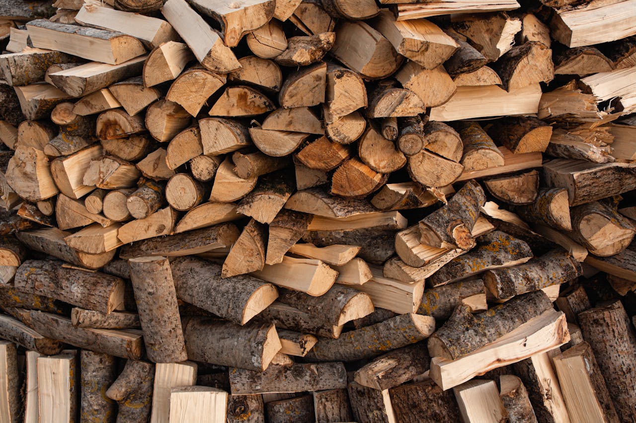 Close-up of a neatly stacked pile of chopped firewood logs, outdoors in natural light.